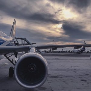 A passenger airplane is parked on the tarmac at sunset, with another aircraft in the background.